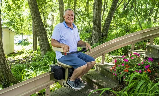 man in a blue shirt riding an outdoor stair lift