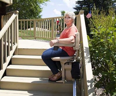 Woman sitting on a Bruno Elite outdoor straight stairlift halfway up the steps