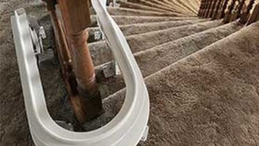 Bruno Elite Curved indoor stairlifts park position option at the top of some steps with brown carpet