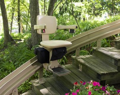Bruno Elite Curved outdoor stairlift parked on a custom stairlift rail above wooden steps