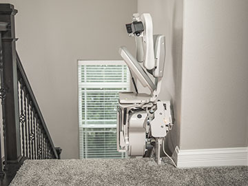 Bruno Elite Curved indoor stairlift parked at the top of the steps with the seat folded up