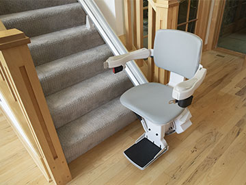 Bruno Elite straight indoor stairlift parked at the bottom of a staircase on a wooden floor
