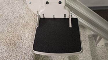 Bruno Elite straight indoor stairlifts larger footrest in front of carpeted steps