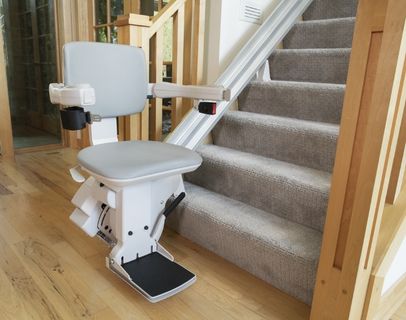 Bruno Elite straight indoor stairlift parked at the bottom of carpeted steps to show that Bruno rental stairlifts can be installed to save space