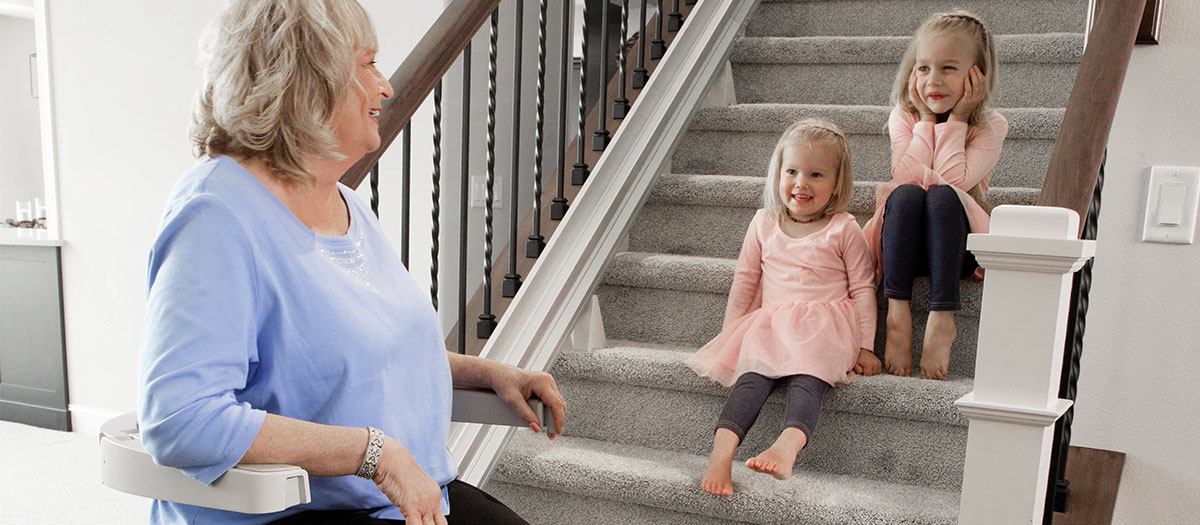 Woman using a Bruno stairlift rental to enjoy more time with her granddaughters
